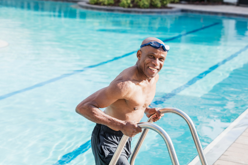 Senior African-American man climbing out swimming pool